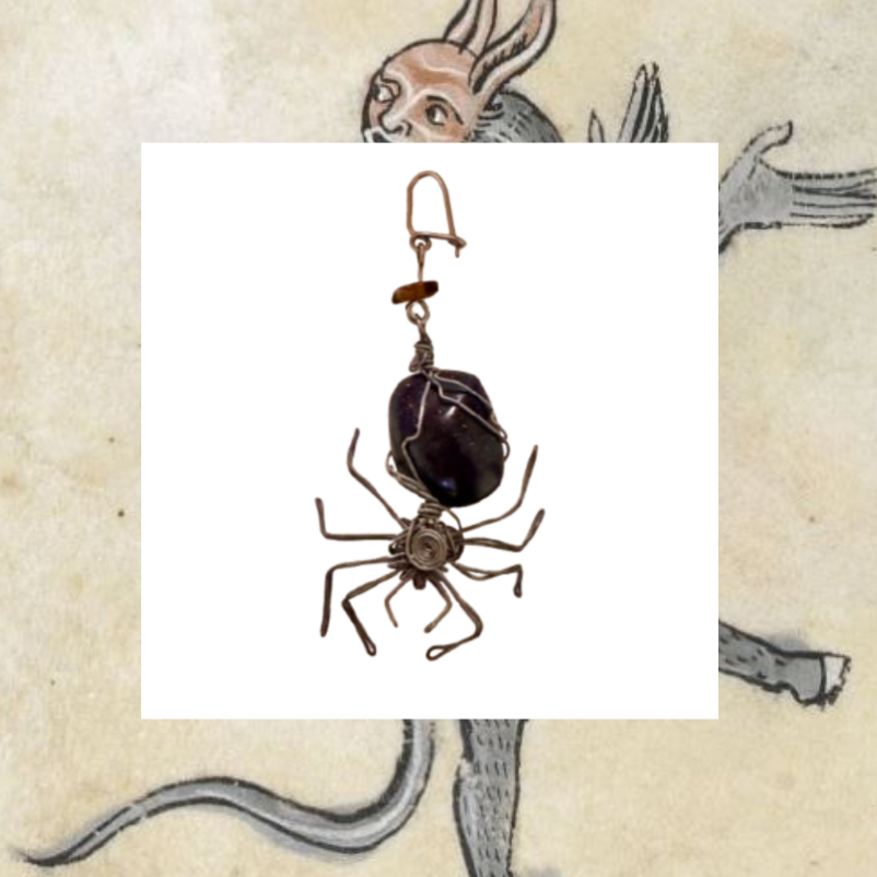 Spider-shaped earring with dark stone on a white background, with a vintage-style illustration of a rabbit and snake in the background.
